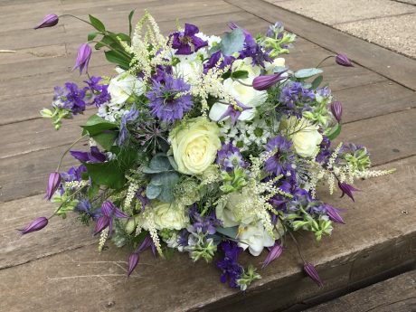 ‘Just picked’ wedding bouquet in blues and whites, consisting of large headed ivory roses, blue nigella flowers, fluffy white astillbe mixed with tiny daisies, scented white freesia and clematis.