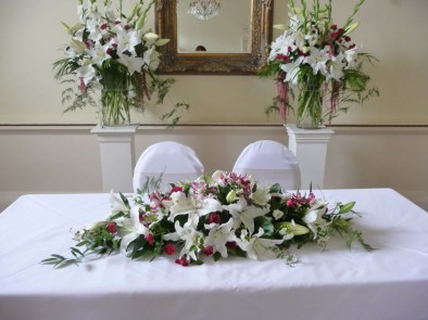 Wedding ceremony set-up with a ‘long & low’ arrangement and two large vases of scented flowers.